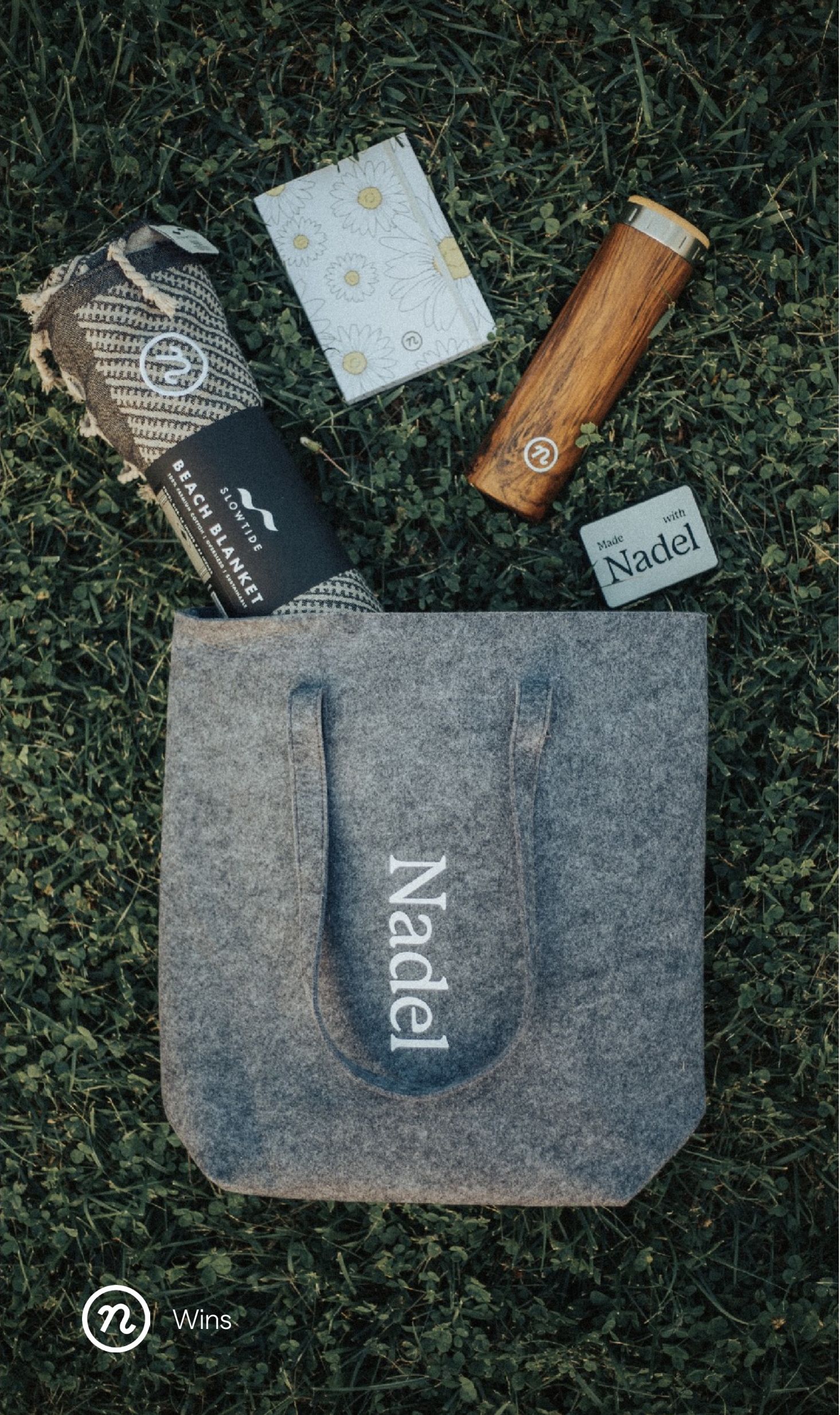 Eco-friendly Nadel products on grass — beach blanket, notebook, wooden tumbler, tote bag